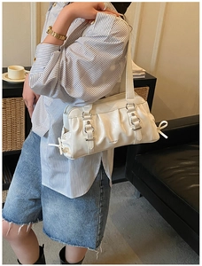 Detail view of cream pleated shoulder bag with silver buckle and delicate side bow tie