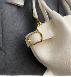 Nahaufnahme der weißen Lederstruktur und der goldenen Metallbeschläge der Handtasche