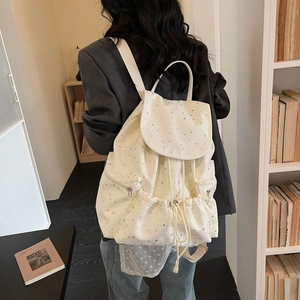 Detailed back view of a white canvas star-patterned backpack with drawstring closure