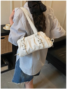 Side view of a white ruched underarm bag on a model wearing a striped shirt
