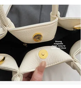 Makro-Detail der hochwertigen goldenen Magnetschnalle und weißen Lederhandtasche