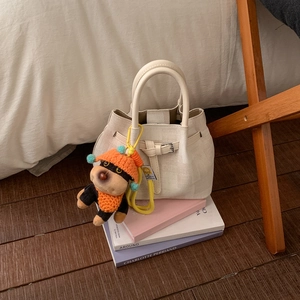 Cream canvas bucket bag with orange dog charm on art books in a warm minimalist setting