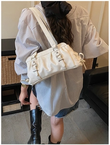 Detailed model view of the cream white pleated underarm bag with silver hardware buckle