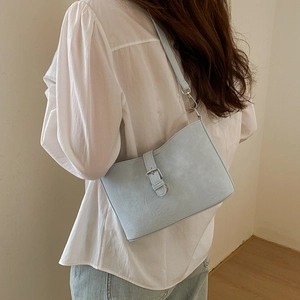 Side view of light blue retro shoulder bag with silver buckle on a female model