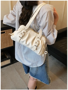 Detail of off-white pleated leather shoulder bag with buckle and model styling