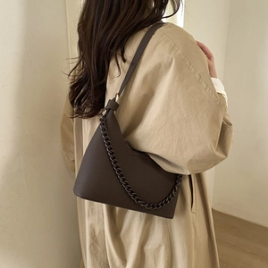 Brown textured leather chain shoulder bag for women styled with a beige trench coat