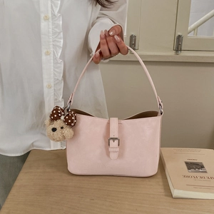Close-up of pink underarm bag with silver buckle and cute teddy bear charm detail