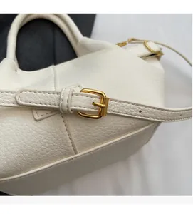 Detailaufnahme der weißen Lederstruktur mit Lychee-Muster und goldener Metallschnalle