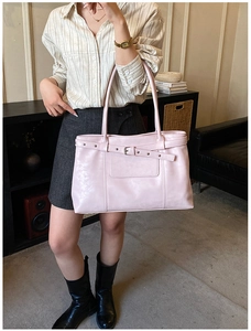 Detail view of pink tote bag showing metal eyelet buckle and smooth synthetic leather texture