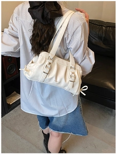 Chic white pleated shoulder bag with silver buckles shown on a model in a modern interior
