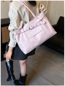 Detail of cherry pink tote bag with leather strap buckle and silver metal grommets