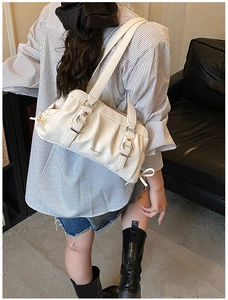 Close-up of white pleated leather underarm bag with decorative silver buckle straps