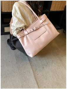 Detail of light pink tote bag featuring a decorative belt buckle and matte leather texture