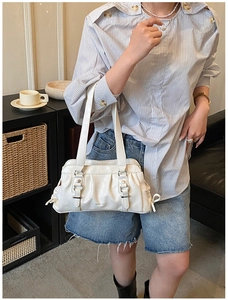 Detail of white pleated faux leather shoulder bag with vintage silver metal buckles