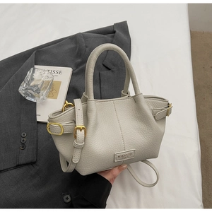 Detailansicht der beige Lederhandtasche mit Lychee-Maserung und goldenen Beschlägen