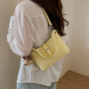 Detail view of yellow faux leather shoulder bag with lychee texture and bear charm
