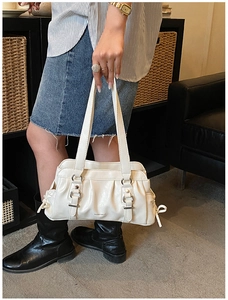 Detail showing the creamy white leather texture and elegant front pleats on the bag