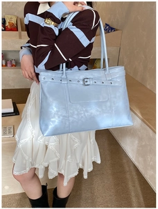 Detail of light blue leather tote bag with silver buckle and adjustable strap