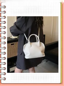 Back view of a model wearing a white pebbled leather shell bag with adjustable strap