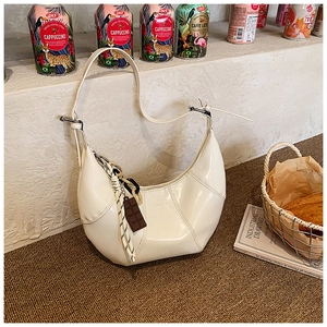 Detailed shot of cream white glossy underarm bag with unique chocolate charm on white stairs