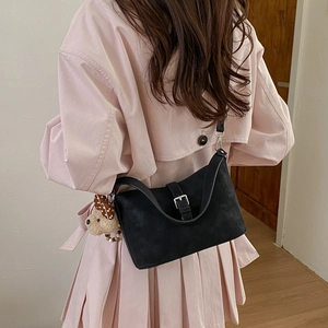 Detail of retro black matte shoulder bag featuring a silver buckle and cute bear pendant