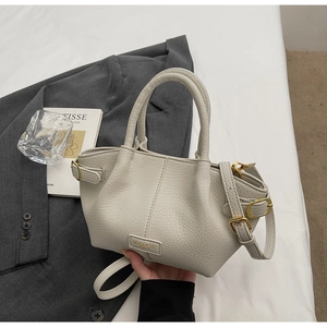 Detailansicht der beigefarbenen Handtasche aus Leder mit goldener Hardware und Logo