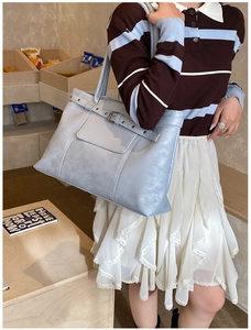 Detail view of the light blue leather tote bag showing the metal buckle and retro belt design