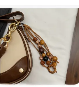 Detail of saddle bag featuring a gold chain strap and a bohemian beaded tassel pendant