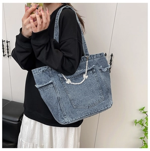 Close-up of washed denim tote bag featuring a pearl chain with white bow decoration