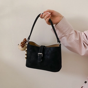 Close-up of black retro underarm bag with silver buckle and cute plush bear charm