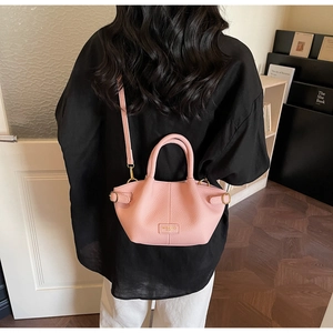Lifestyle-Aufnahme eines Models mit der rosa Leder-Beuteltasche in einem modernen Raum