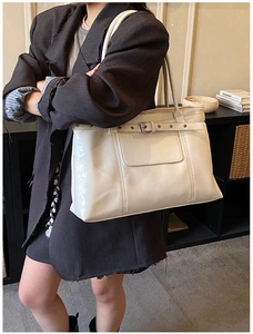 Detail of creamy white PU leather tote bag with stylish buckle and stitching details