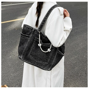 Close-up of washed denim tote bag featuring vintage frayed edges and a pearl bow chain