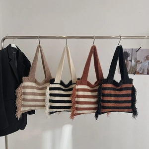 Detail of striped knitted tote bags with side tassels and soft woven texture in earth tones