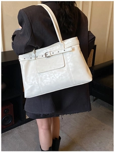 Rear view of model wearing a white high-shine leather tote bag with silver buckle detail