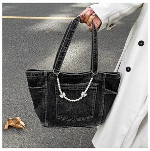 Close-up of dark grey denim tote bag with decorative pearl chain and silver bow detail