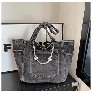 Detail of washed denim tote with frayed edges, pearl handle, and ribbon bow accent