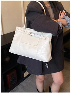 Detail of white PU leather tote bag featuring stylish silver buckle belt and eyelet straps