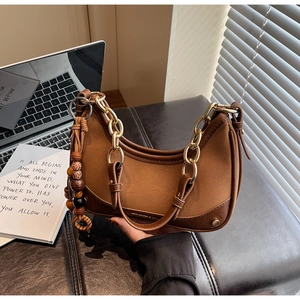 Détail du sac dumpling vintage marron avec chaîne dorée et pendentif à glands