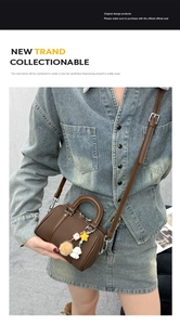 Detail of dark brown mini Boston bag with plush charms worn crossbody by a model