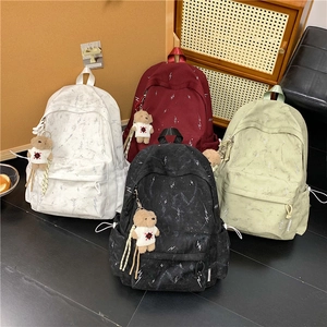 Detail of four colorful student backpacks with creative patterns and plush bear charms