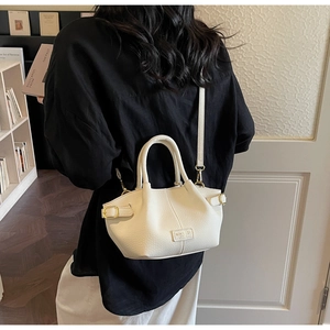 Detail der cremefarbenen Ledertasche mit goldener Hardware und Logo im Lifestyle-Szenario