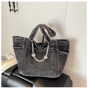 Detail of grey washed denim tote bag featuring fringe edges and pearl bow chain