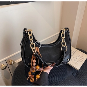 Détail du sac hobo noir avec chaîne dorée et pendentif à pampilles en perles colorées