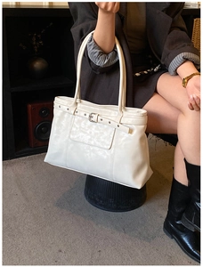 Detailed view of white faux leather tote bag with decorative belt buckle and retro design