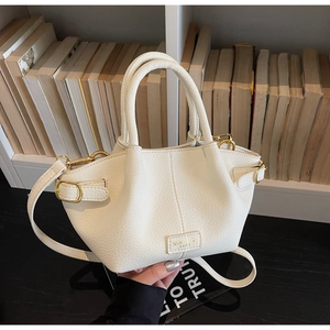 Nahaufnahme der weißen Lederhandtasche mit Lychee-Muster, Goldener Schnalle und Markenlogo