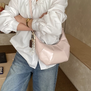 Detail of pink glossy crescent bag with geometric stitching and decorative charms