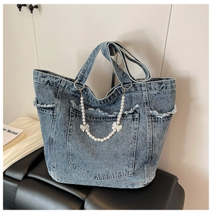 Detail of washed denim tote with pearl chain, silver bows and raw edge outer pocket