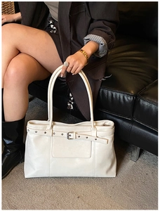 Detail view of cream tote bag with silver buckle strap and leather texture finish