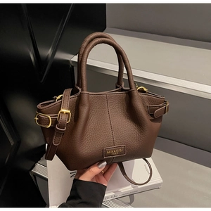 Detailaufnahme der dunkelbraunen Lederhandtasche mit feiner Litschi-Struktur und Logo